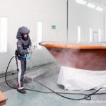 Stefan Baumgart in Schutzkleidung bei Holzlackierarbeiten in der Lackierkabine der Bootswerft Baumgart in Dortmund