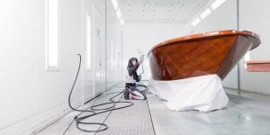 Stefan Baumgart in Schutzkleidung bei Holzlackierarbeiten in der Lackierkabine der Bootswerft Baumgart in Dortmund