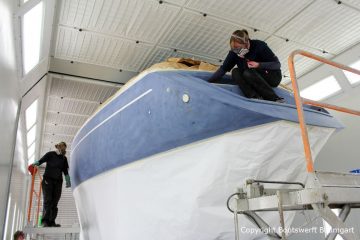 Fertig geschliffene Comfortina 38 Segelyacht vor der Lackierung in der grossen Lackierkabine der Bootswerft Baumgart in Dortmund. Das Unterwasserschiff und das Deck sind bereits mit Papier abgedeckt.