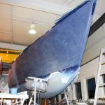 Die erste Lackschicht wird angeschliffen. Die Comfortina 38 in der Bootswerft. Steuerbordseite in der Werfthalle der Bootswerft Baumgart in Dortmund